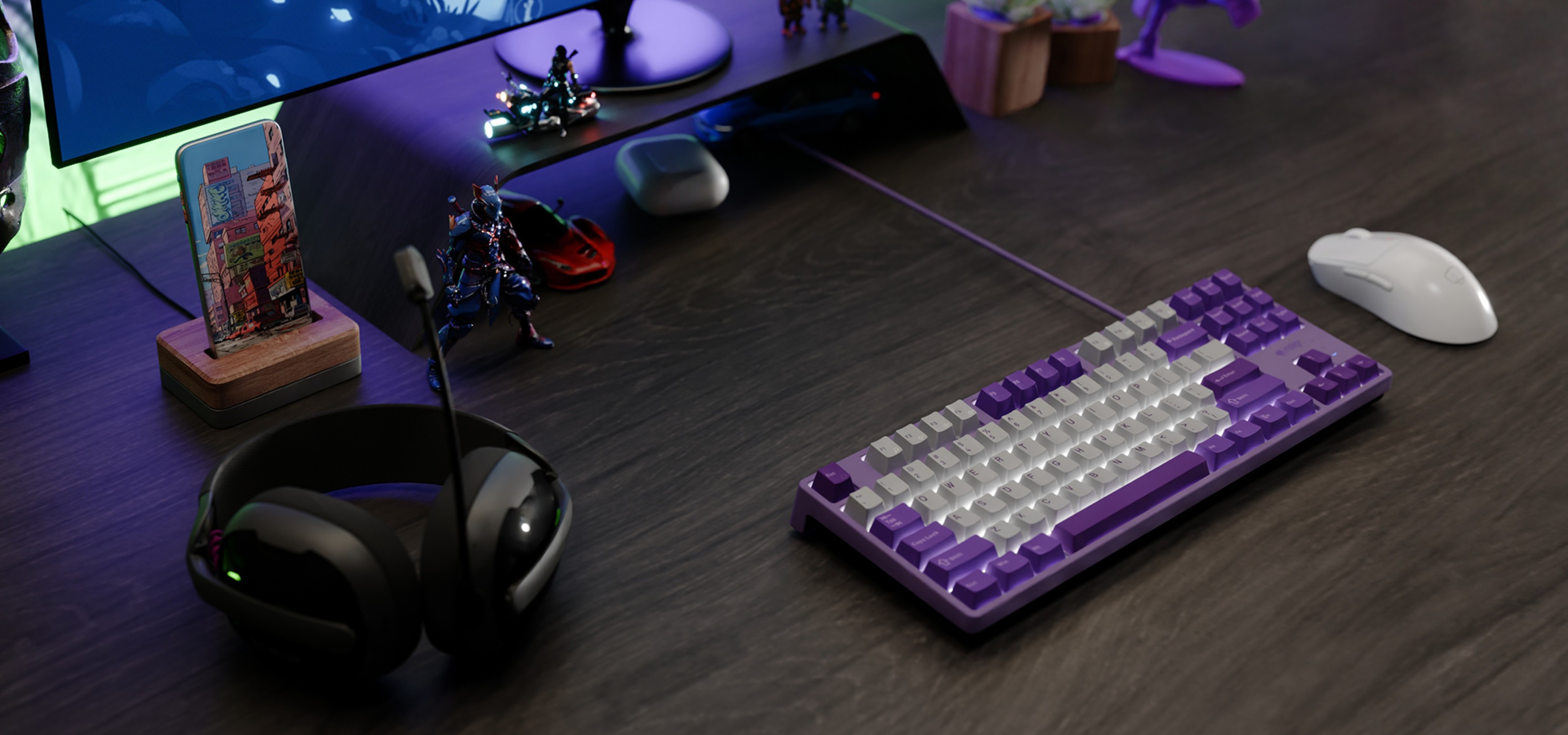 A purple and white keyboard, gaming mouse, and headphones on a dark desk with decorations.