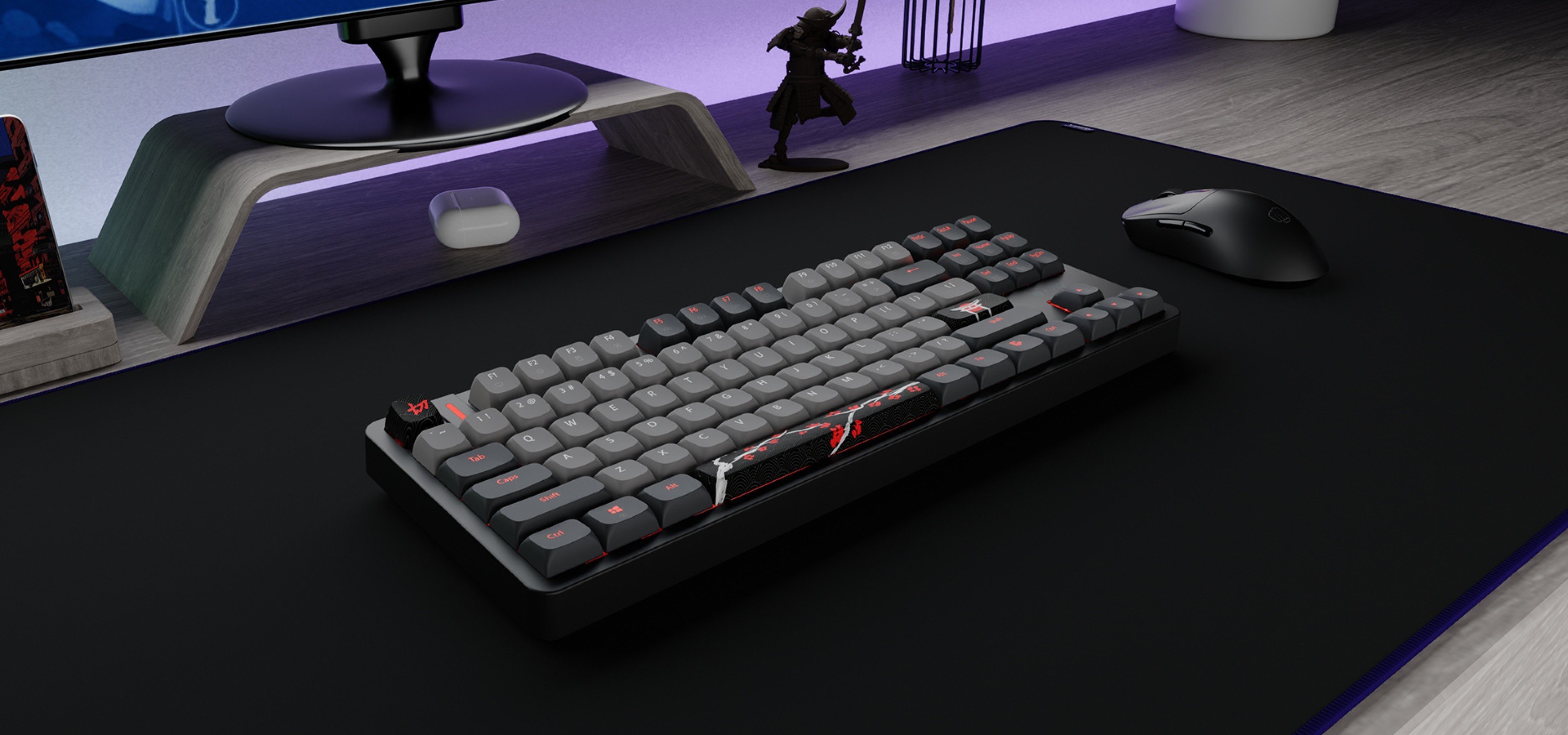 Keyboard with gray keys and red accents placed on a black gaming mouse pad next to a mouse.
